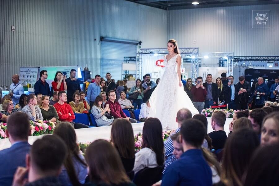 Modelka prezentuje slubną kreację podczas pokazu mody na targach ślubnych.