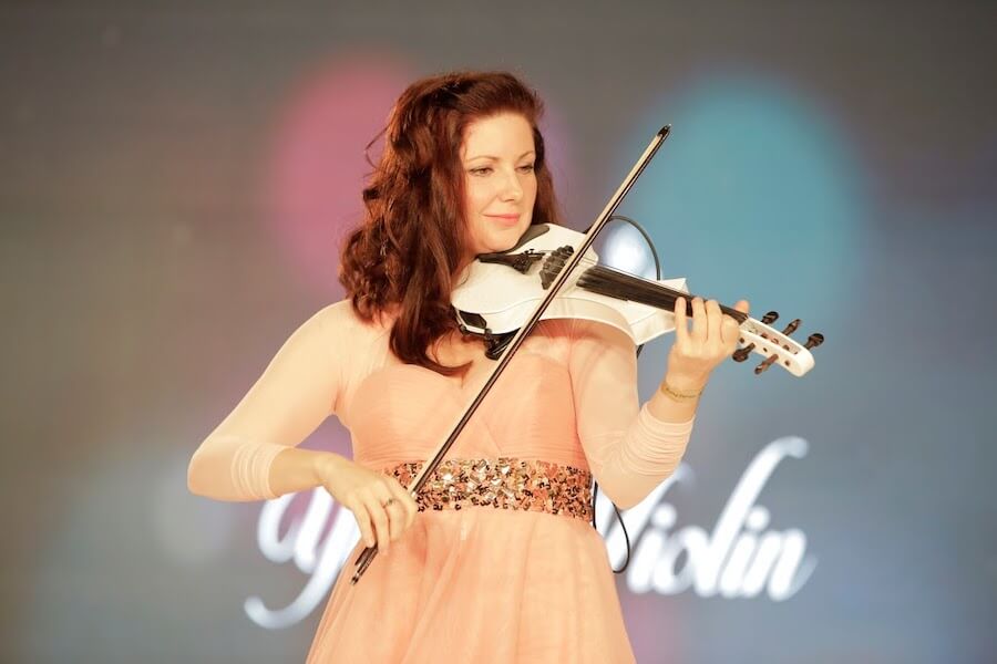 Na scenie targow slubnych występuje kobieta grająca na skrzypcach.