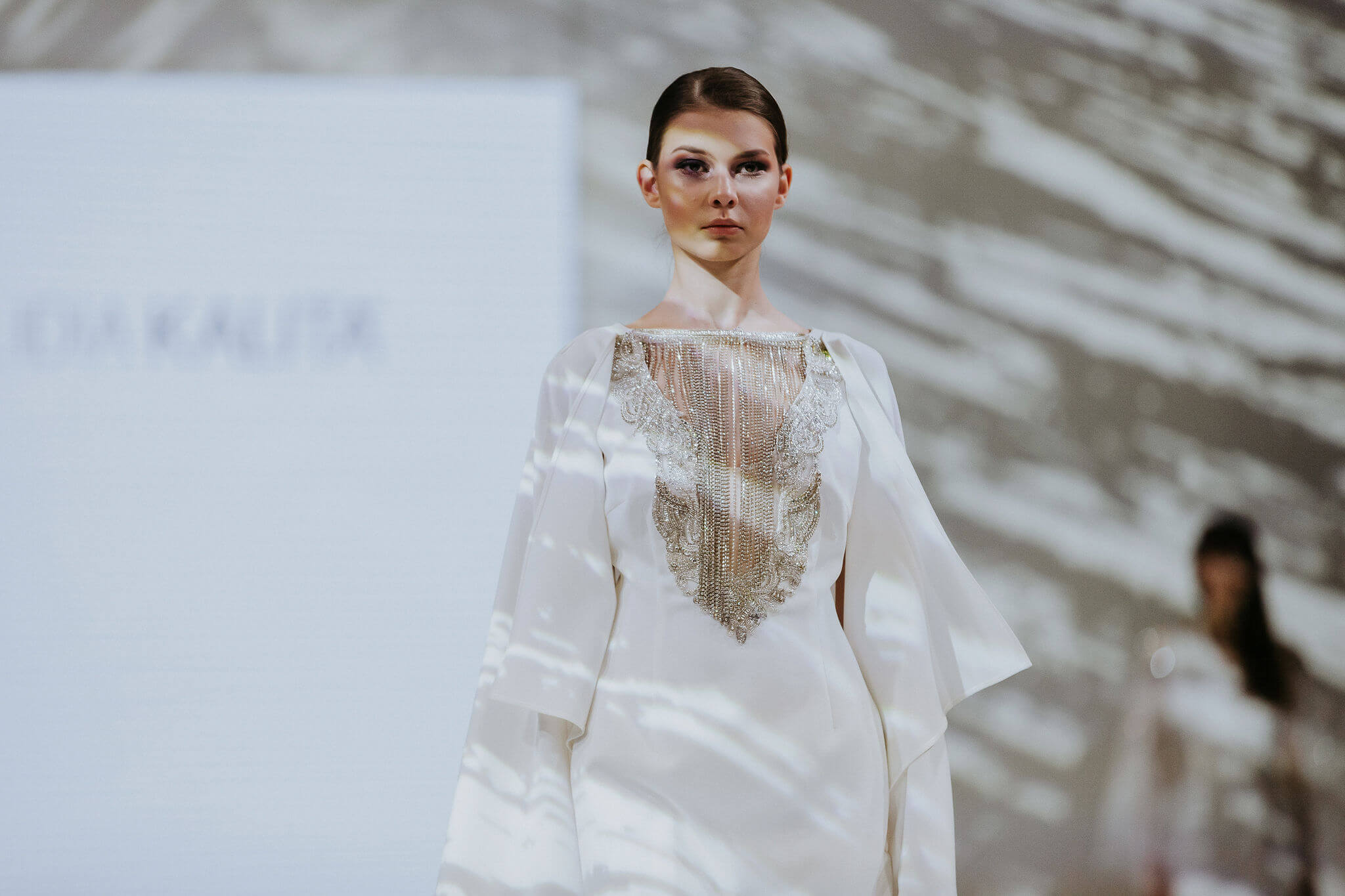 Modelka w białej sukni z brylantowym zdobieniem na scenie warszawskich targow slubnych w EXPO XXI.